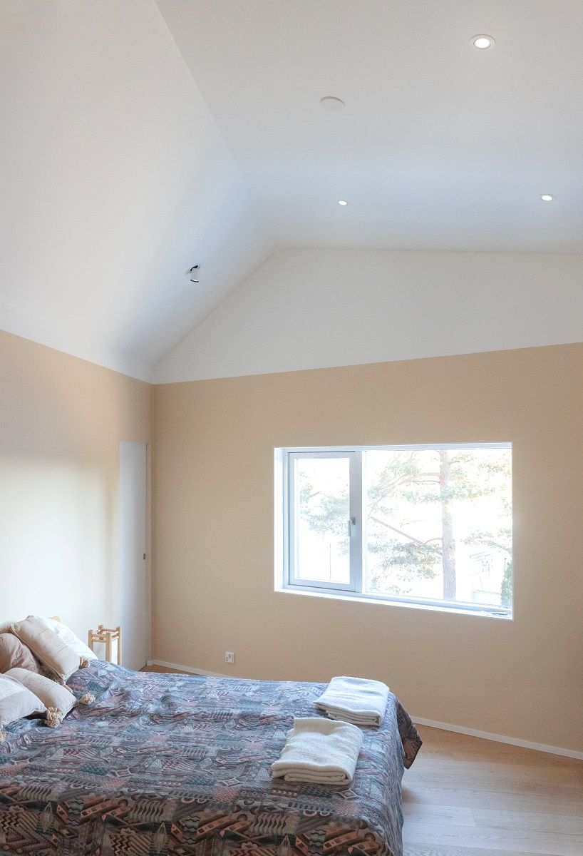 A high bedroom illuminated by directional flush-mounted spotlights, and KOLO spotlights.